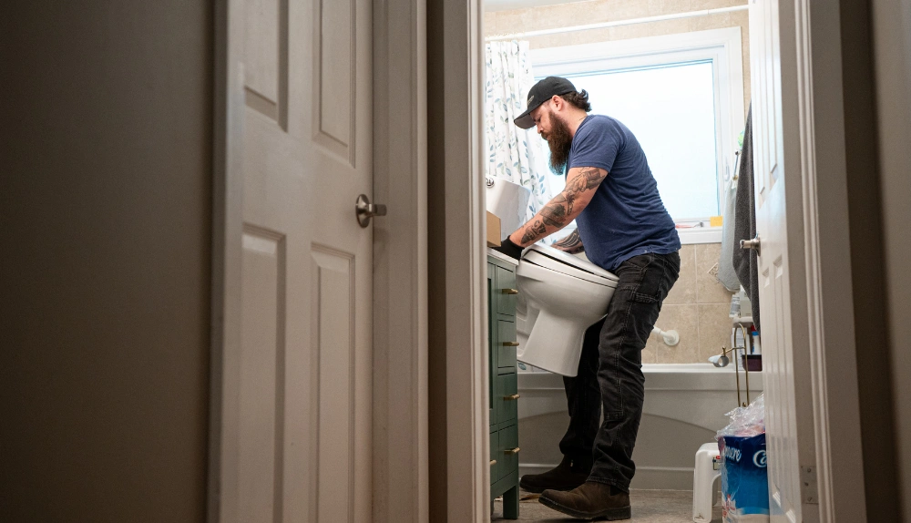 Bytown installer fitting a vanity inside a condo bathroom, seen through the unit doorway