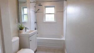 Compact renovated bathroom in an older Vanier home with a white tub-shower, subway tile and a small vanity under a window