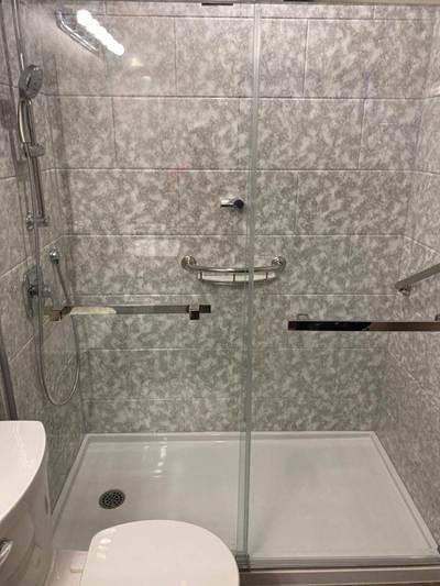 Walk-in shower in an Ottawa bathroom with tile, grab bars and a glass door